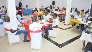 A conference room with round tables, white chairs, and attendees seated. - DF Plazza Hotel (Yaoundé)