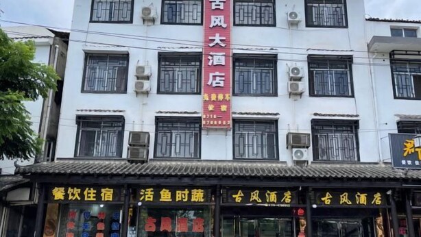 Un hôtel reconnaissable à son grand panneau rouge, à ses nombreuses fenêtres et à ses unités de climatisation.