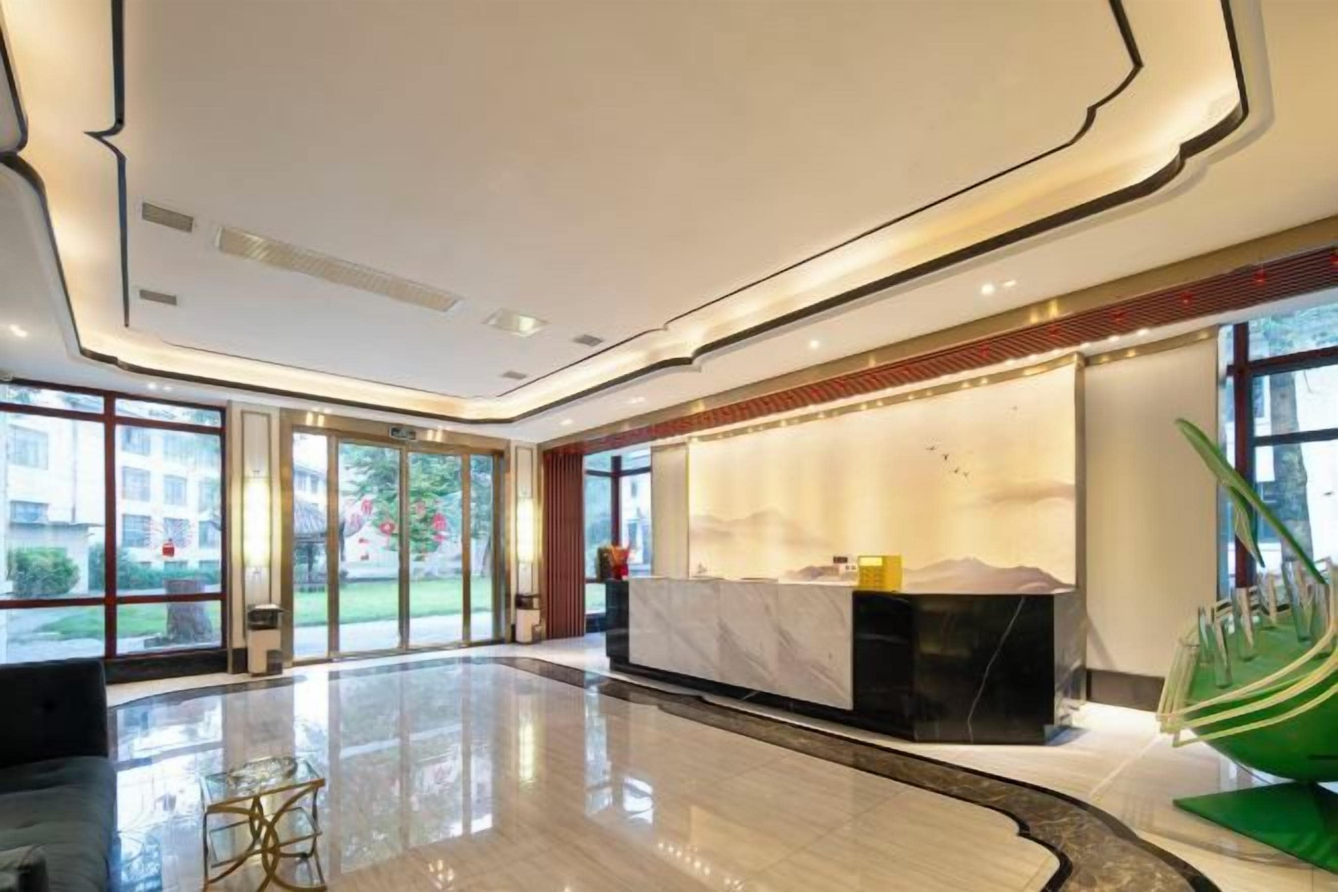 A hotel lobby with a reception desk, a seating area, and large windows.