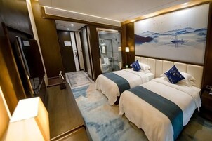 A hotel room with two beds, a large painting, and a view of a mountainous landscape.