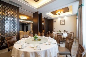 Un espace repas avec des tables rondes, des chaises et un élément décoratif central.