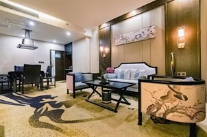 Una habitación de hotel moderna con sofá, una mesa de centro y un comedor con sillas.