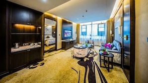 A modern hotel room with a large bed, a TV, a seating area with a sofa and armchairs, and a large window offering a view. - TONGXINLAKE HOTEL (You County)
