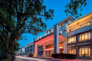 Un hotel con fachada moderna, varios pisos y una entrada destacada con señalización iluminada.