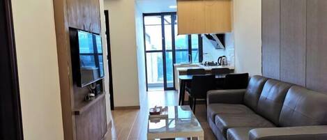 A modern living room with a leather sofa, a small coffee table, and a TV on a wooden cabinet.