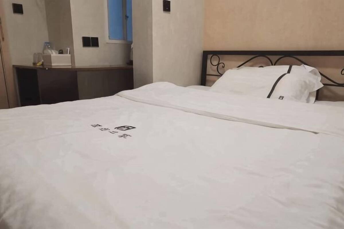 Una habitación de hotel con cama, mesita de noche, espejo y ventana.