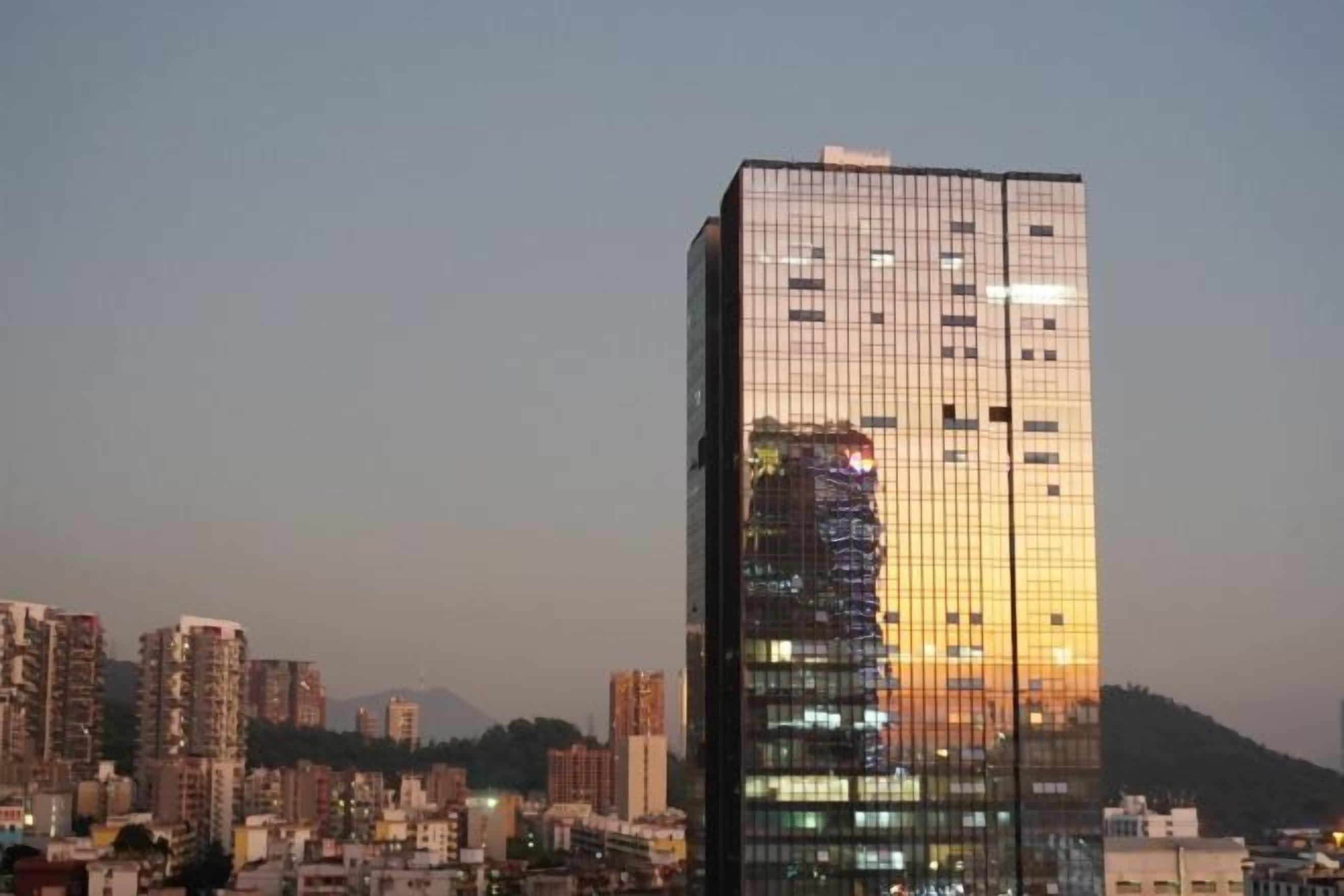 A high-rise building with a modern glass facade, surrounded by other buildings.