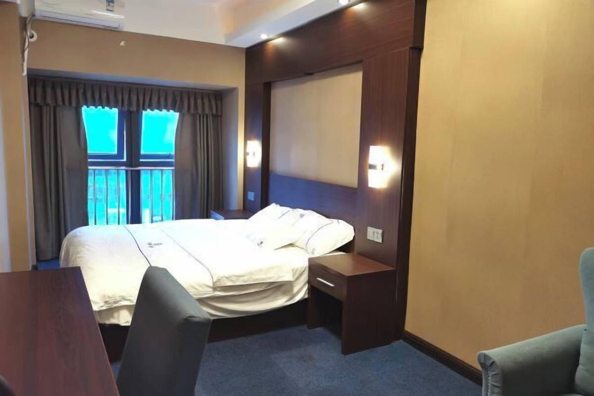 Una habitación de hotel con una cama, mesitas de noche, un escritorio y una silla.