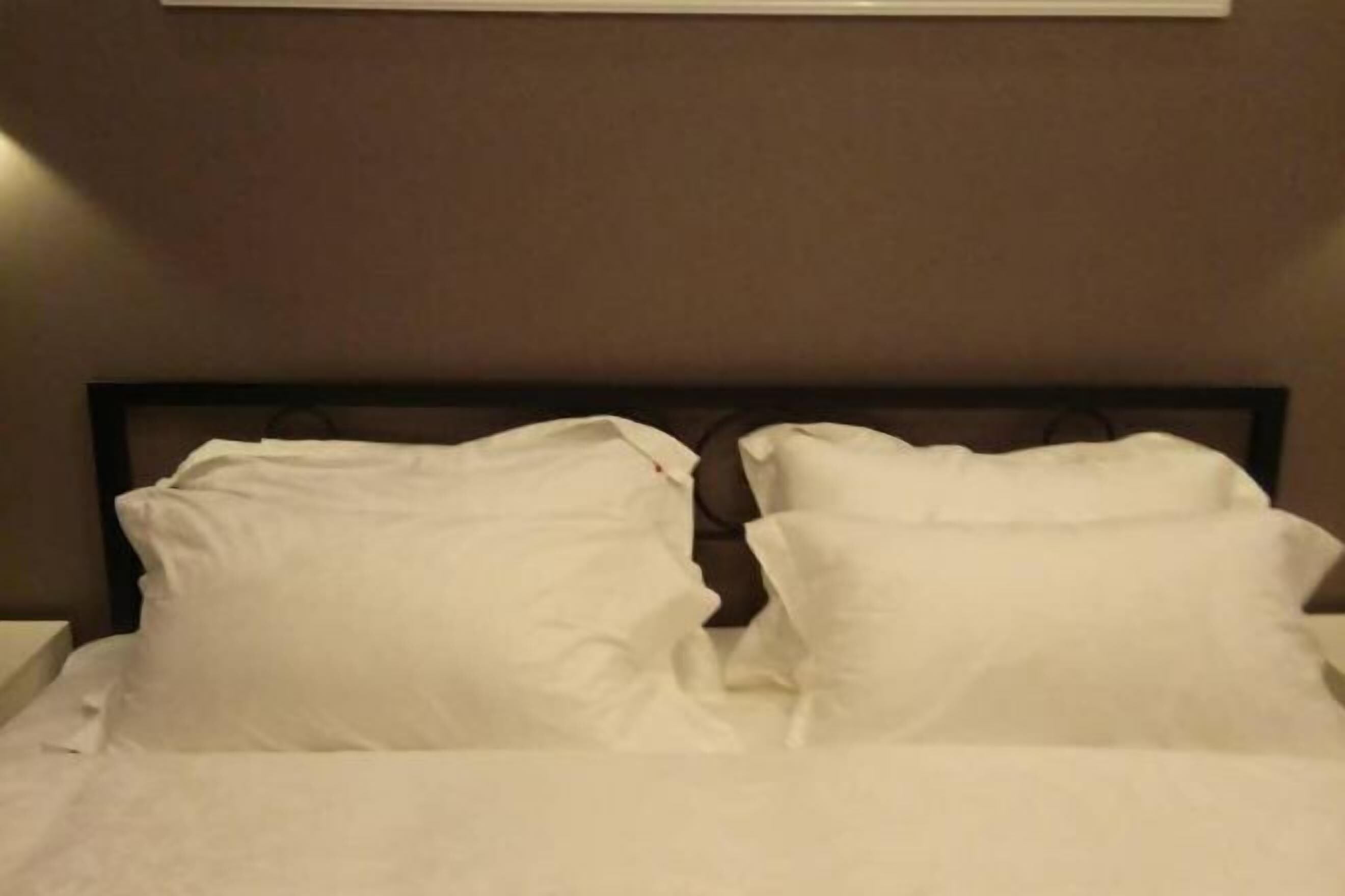 Una cama bien hecha con sábanas blancas y un cabecero oscuro.