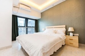Ein modernes Hotelzimmer mit einem großen Bett, Nachttischlampen, einem Beistelltisch und einem Fenster mit Vorhängen.