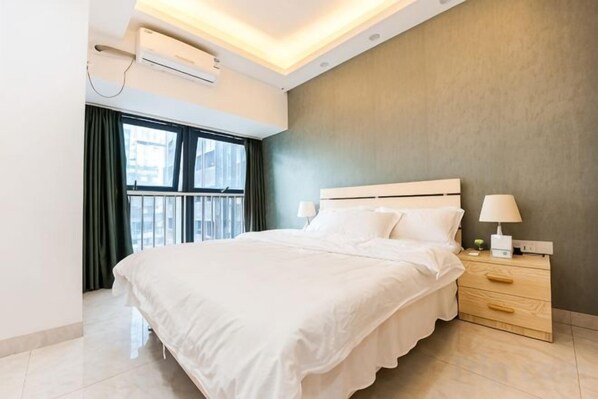 Habitación de hotel moderna con una cama grande, lámparas de noche, una mesita de noche y una ventana con cortinas.