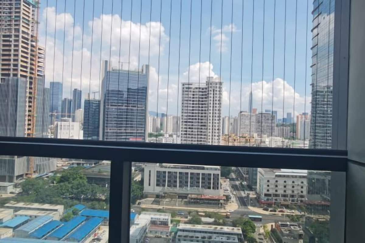 Vista de un paisaje urbano a través de una ventana, con rascacielos, cielo despejado y una construcción en vistas inferiores.