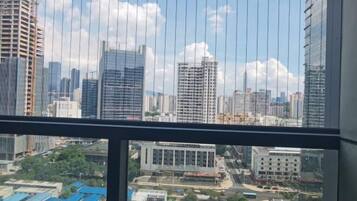 A cityscape through a window with high-rise buildings, a clear sky, and a view of a construction site below.