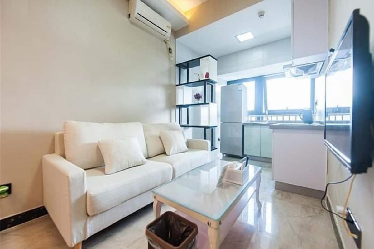 Una sala de estar moderna con un sofá blanco, una mesita de centro de vidrio y un pequeño cubo de basura.