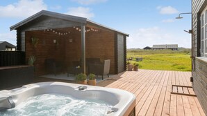 En træhytte med jacuzzi og udendørs siddeplads.