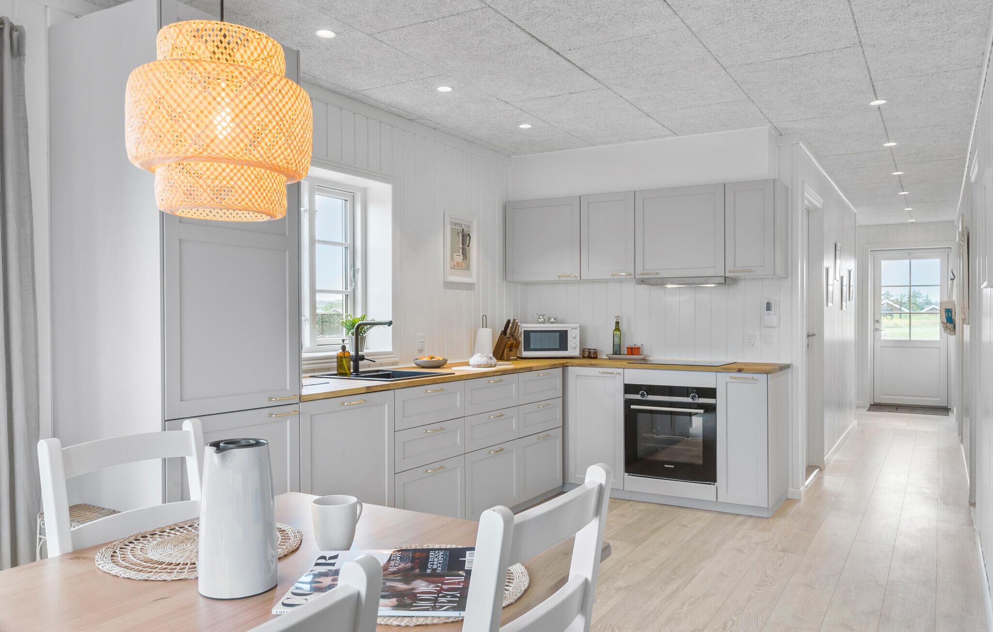 A modern kitchen with white cabinets, a wooden countertop, and a large island with seating.