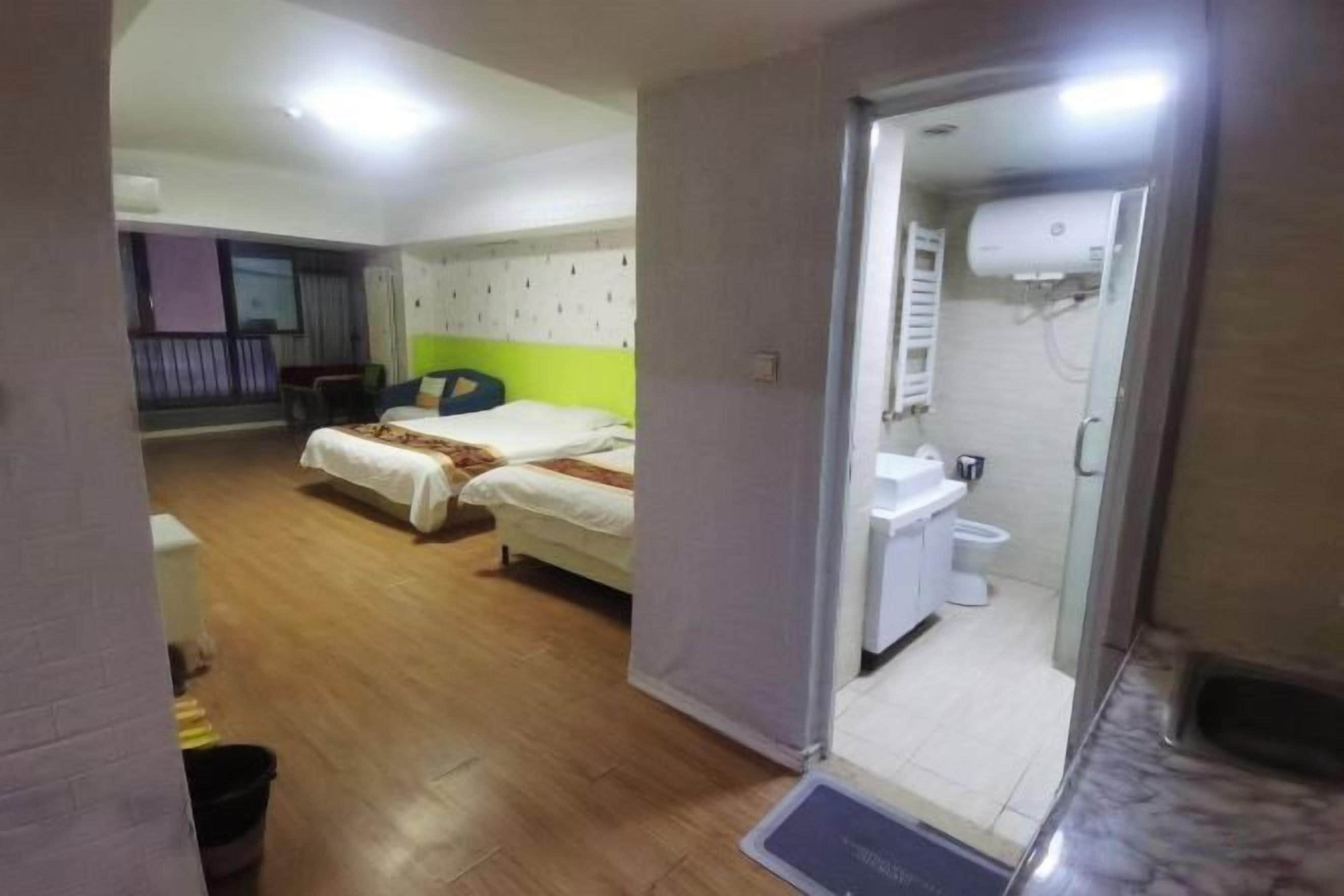 Habitación de hotel con dos camas, baño con ducha y una pequeña zona de estar.