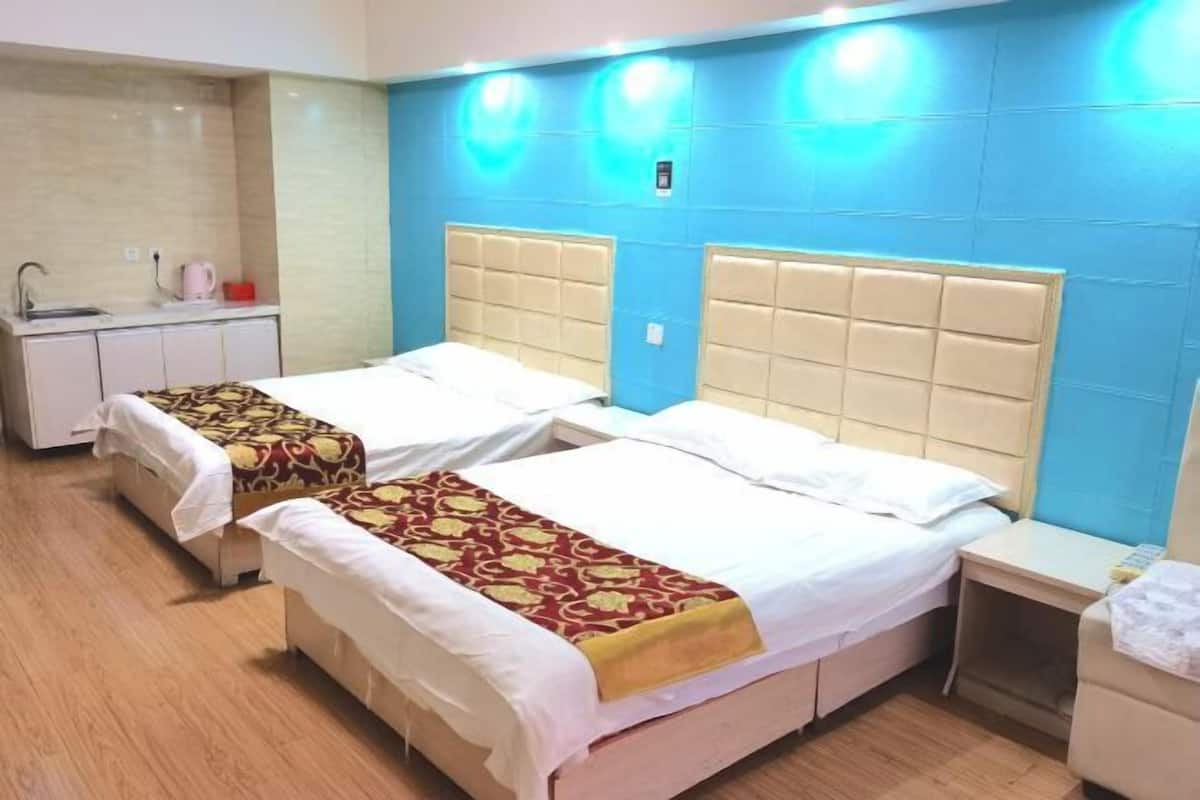 Una habitación de hotel con dos camas, una kitchenette pequeña y una pared azul de acento.