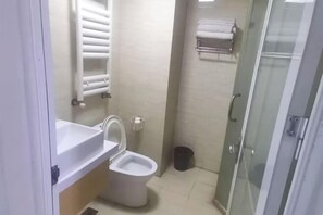 Une salle de bain équipée de toilettes, d’un lavabo et d’une douche à parois de verre.