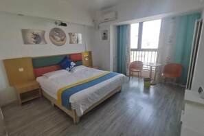 Une chambre d’hôtel avec un lit, une petite table, une chaise et une fenêtre avec des rideaux.