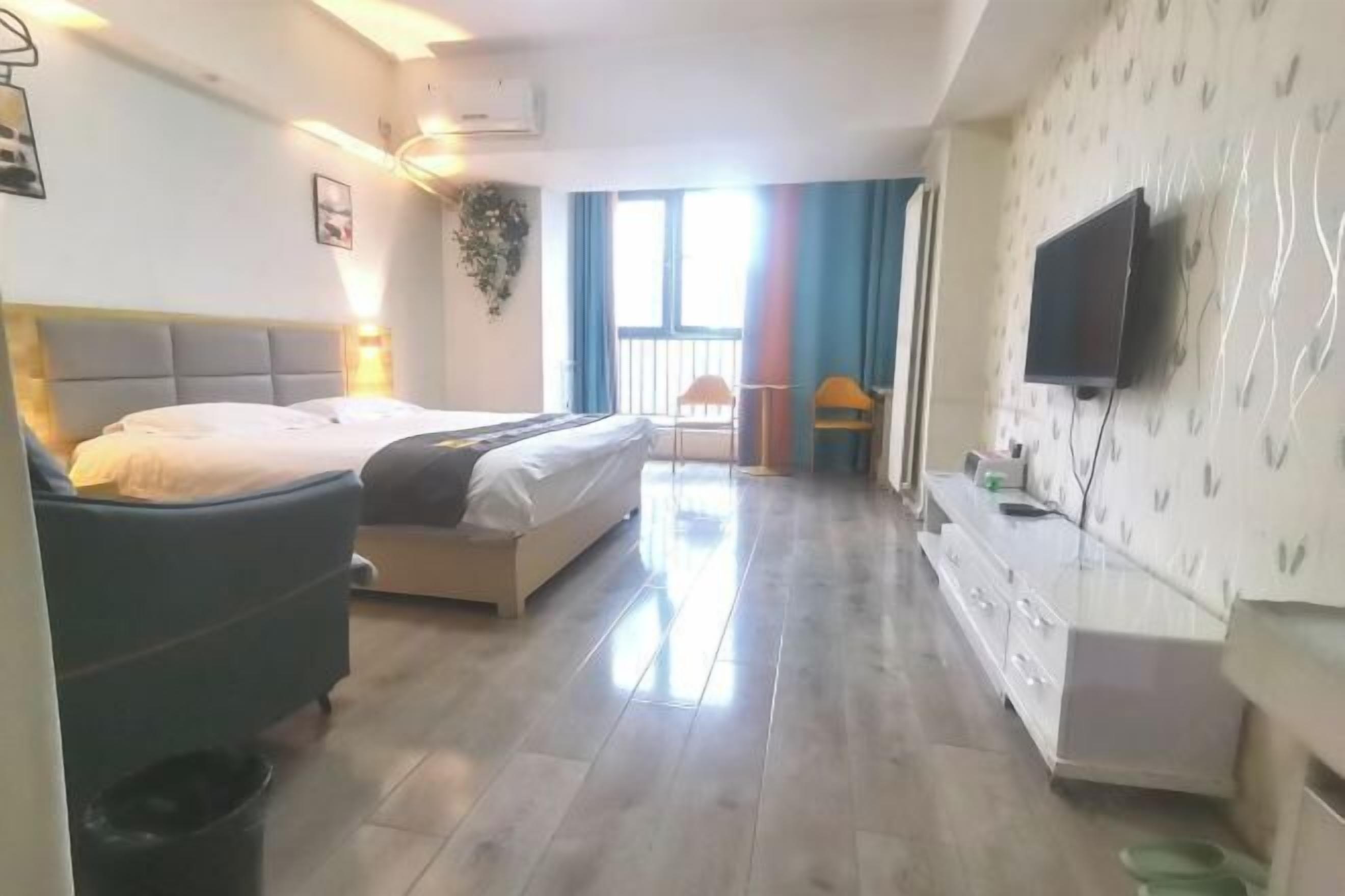 A hotel room with a bed, a desk, a TV, and a window with curtains.