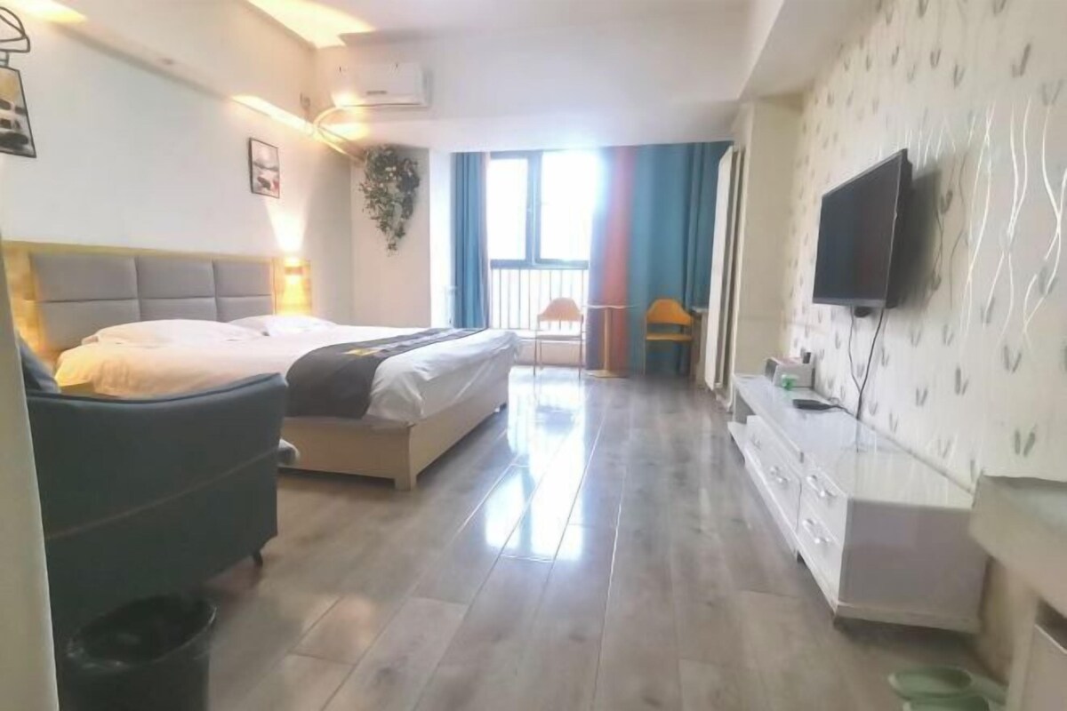 Une chambre d’hôtel avec un lit, un bureau, une télévision et une fenêtre avec des rideaux.