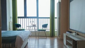 A hotel room with a bed, two chairs, a small table, a TV, and a balcony with a railing. - Zhengzhou Wanda Hotel (Erqi Wanda) (Zhengzhou)