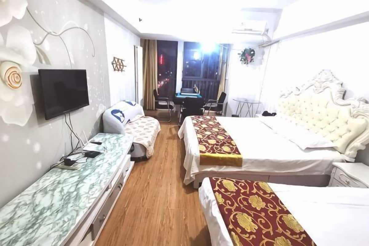 Habitación de hotel con dos camas, un escritorio, una silla, un televisor y un balcón.