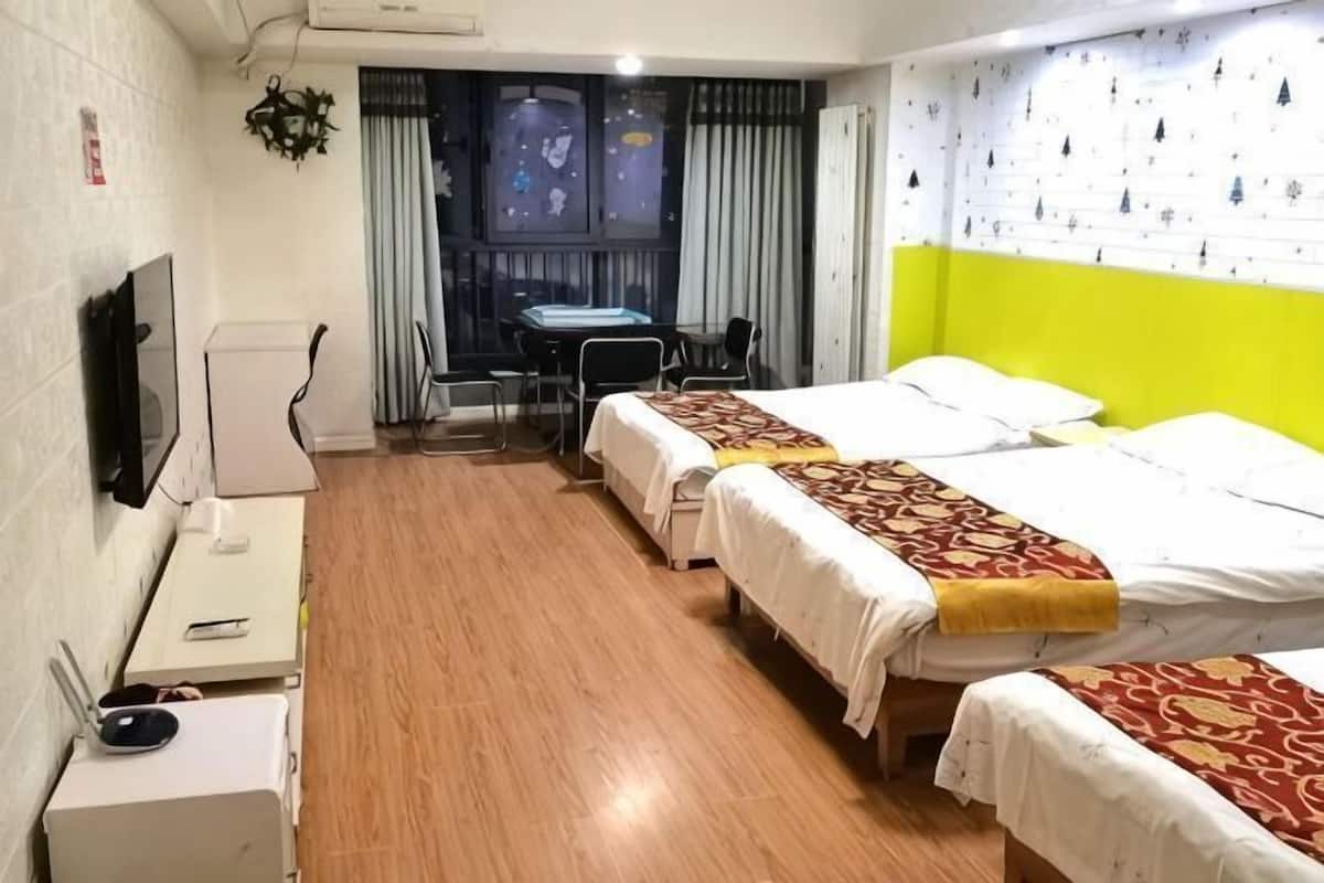 Habitación de hotel con dos camas, un escritorio, una silla, un televisor y una ventana con cortinas.