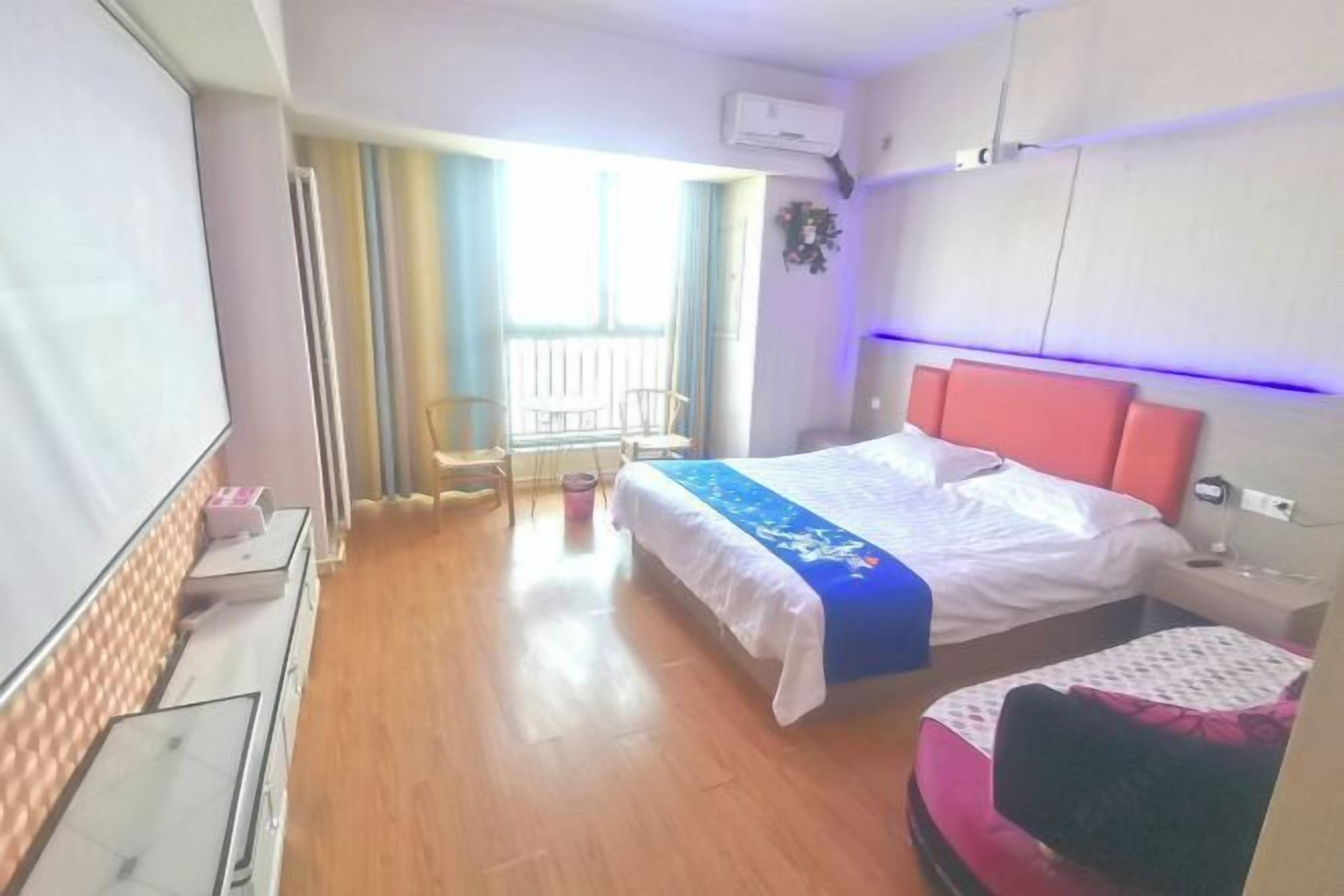 Hotellihuone, jossa on sänky, työpöytä, tuoli ja ikkuna, jossa on verhot.