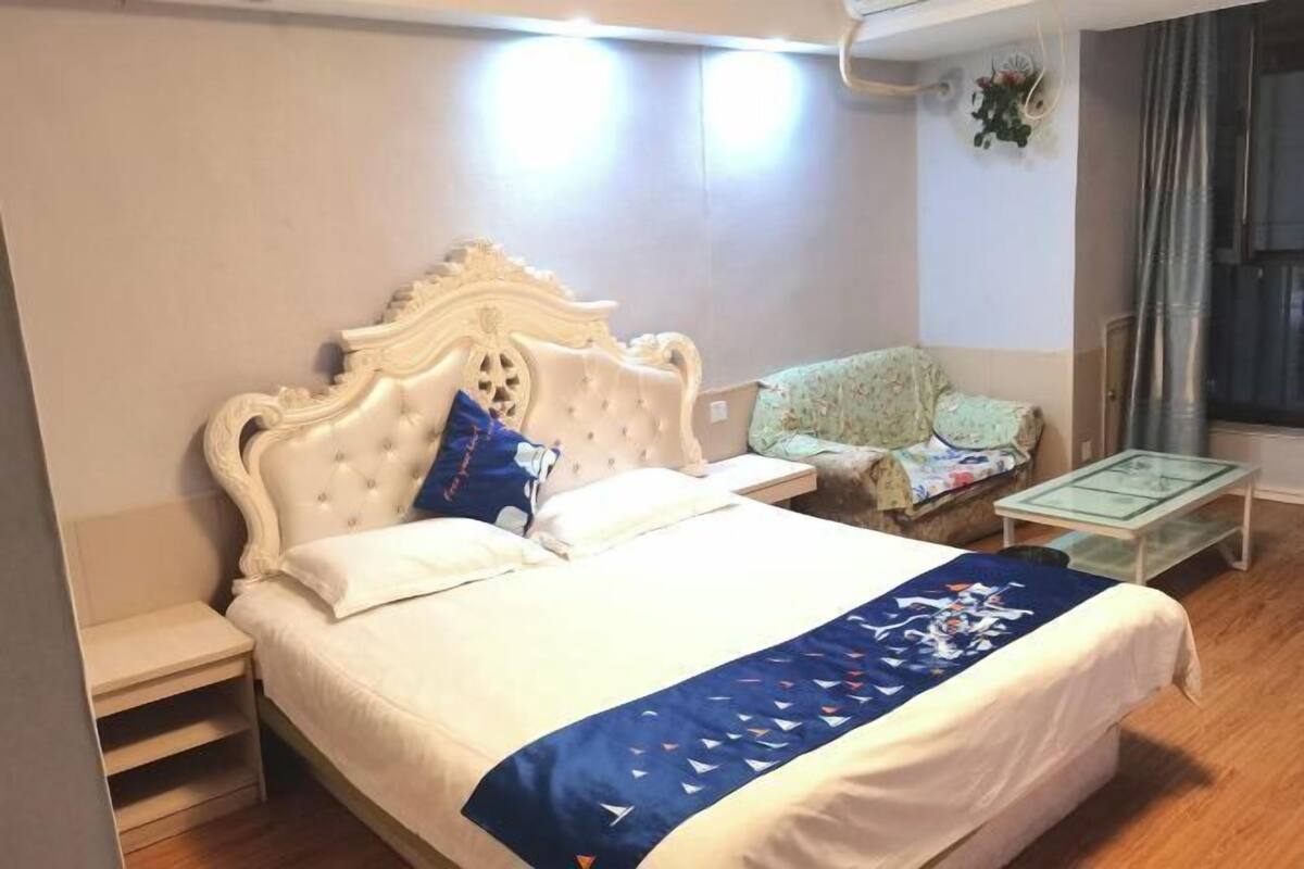 Un dormitorio con una cama grande, una mesita de noche, una silla y una pequeña mesa.