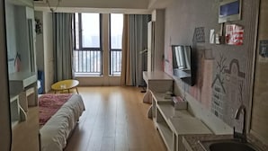 A modern hotel room with a bed, a small desk, a TV, and a large window with curtains. - Zhengzhou Wanda Hotel (Erqi Wanda) (Zhengzhou)