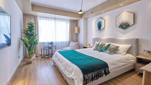 A modern bedroom with a large bed, bedside tables, a potted plant, and a window with curtains. - Zhengzhou Wanda Hotel (Erqi Wanda) (Zhengzhou)