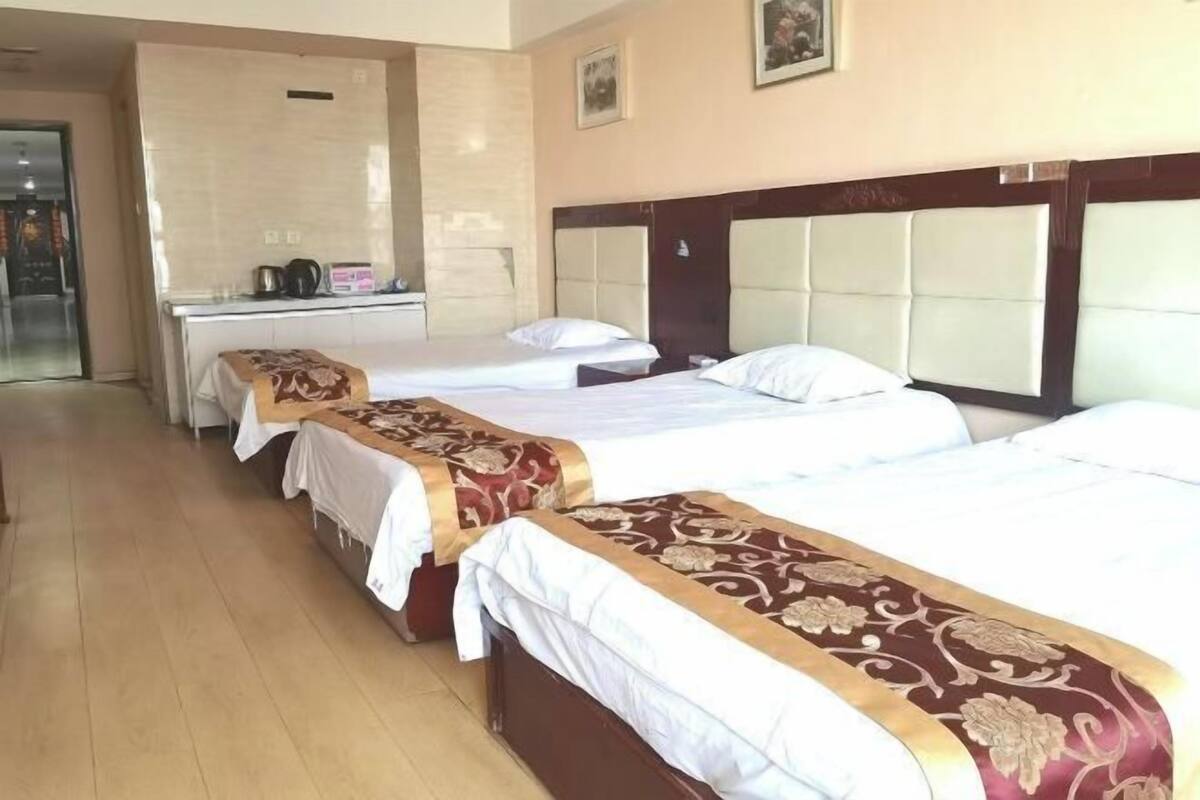 Habitación de hotel con tres camas, kitchenette y baño.
