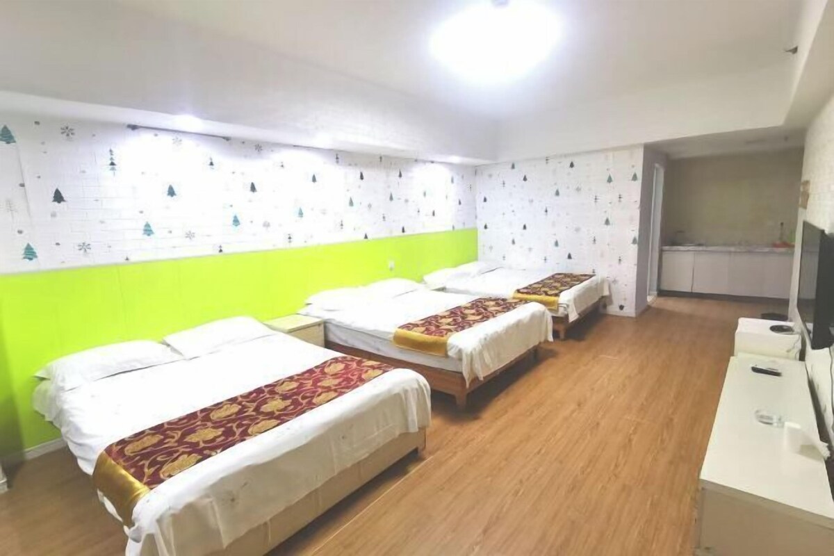 Une chambre d’hôtel avec trois lits, un bureau et une télévision.