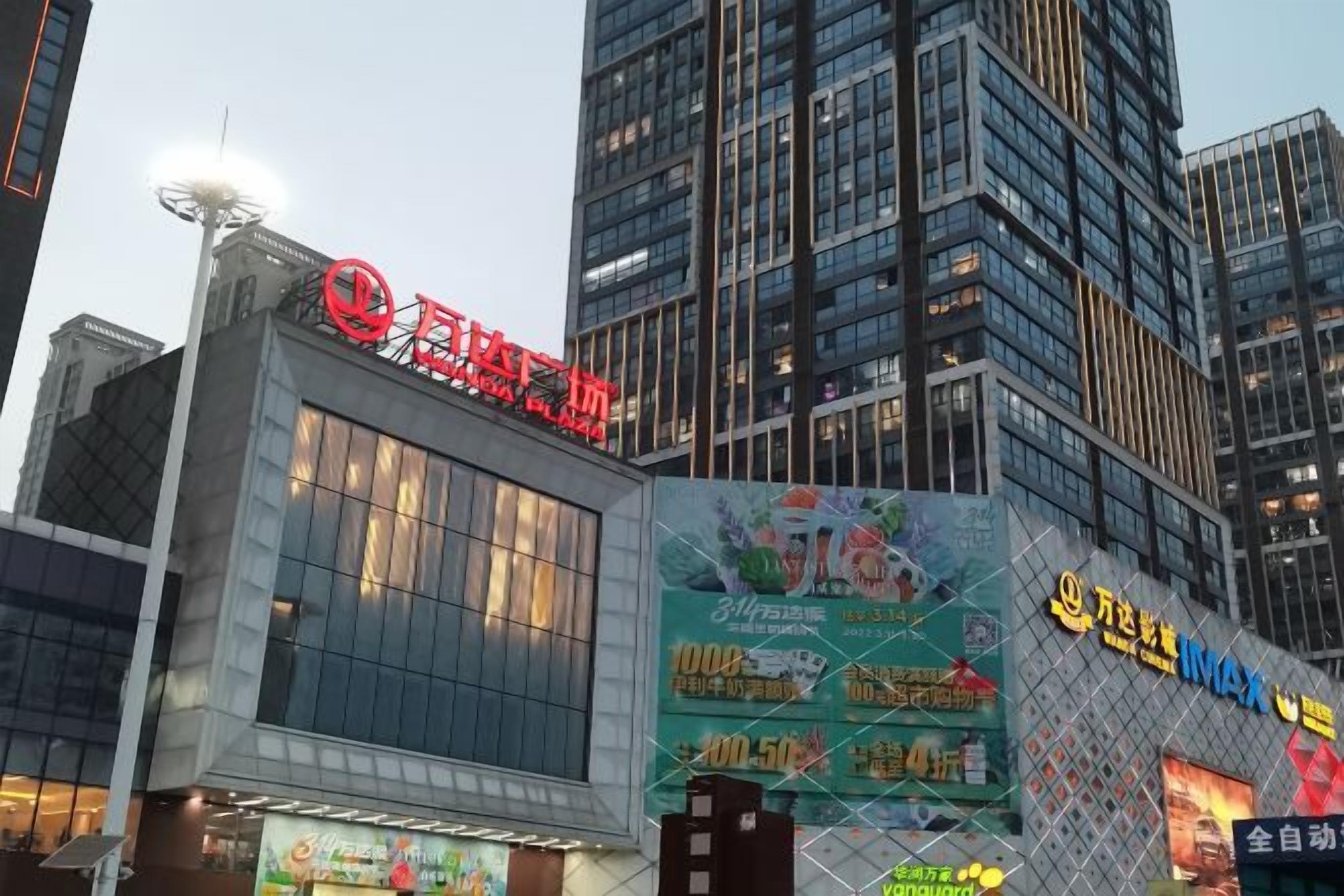 Um edifício com uma placa vermelha chamativa, amplas janelas e um painel de publicidade digital.