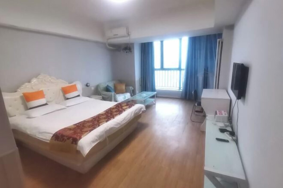 Une chambre d’hôtel avec un lit, un bureau, une chaise, une télévision et une fenêtre avec des rideaux.
