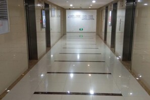 Un passadís amb terra polita, senyals de sortida d'emergència i portes d'ascensor.