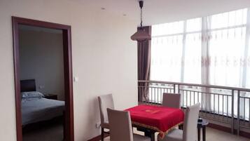 A hotel room with a balcony, a dining table with chairs, and a bed.