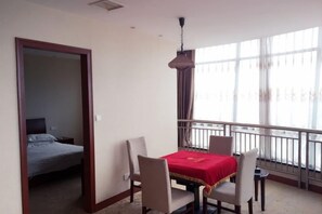A hotel room with a balcony, a dining table with chairs, and a bed. - Wanhao Hotel (Cixi)
