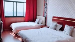 Habitación de hotel con dos camas, un ventanal grande con cortinas rojas, un papel tapiz estampado y vistas a la ciudad.