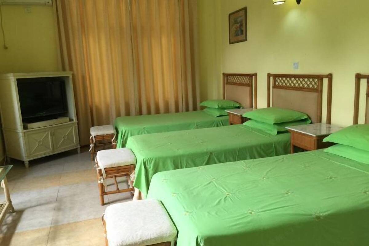 Une chambre d’hôtel avec quatre lits, une télévision et un rideau.