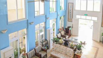 A spacious room with high ceilings, large windows, and a central seating area with a sofa and chairs.