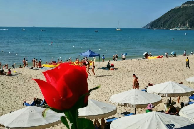 A beach with people, umbrellas, and boats.