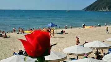 A beach with people, umbrellas, and boats.