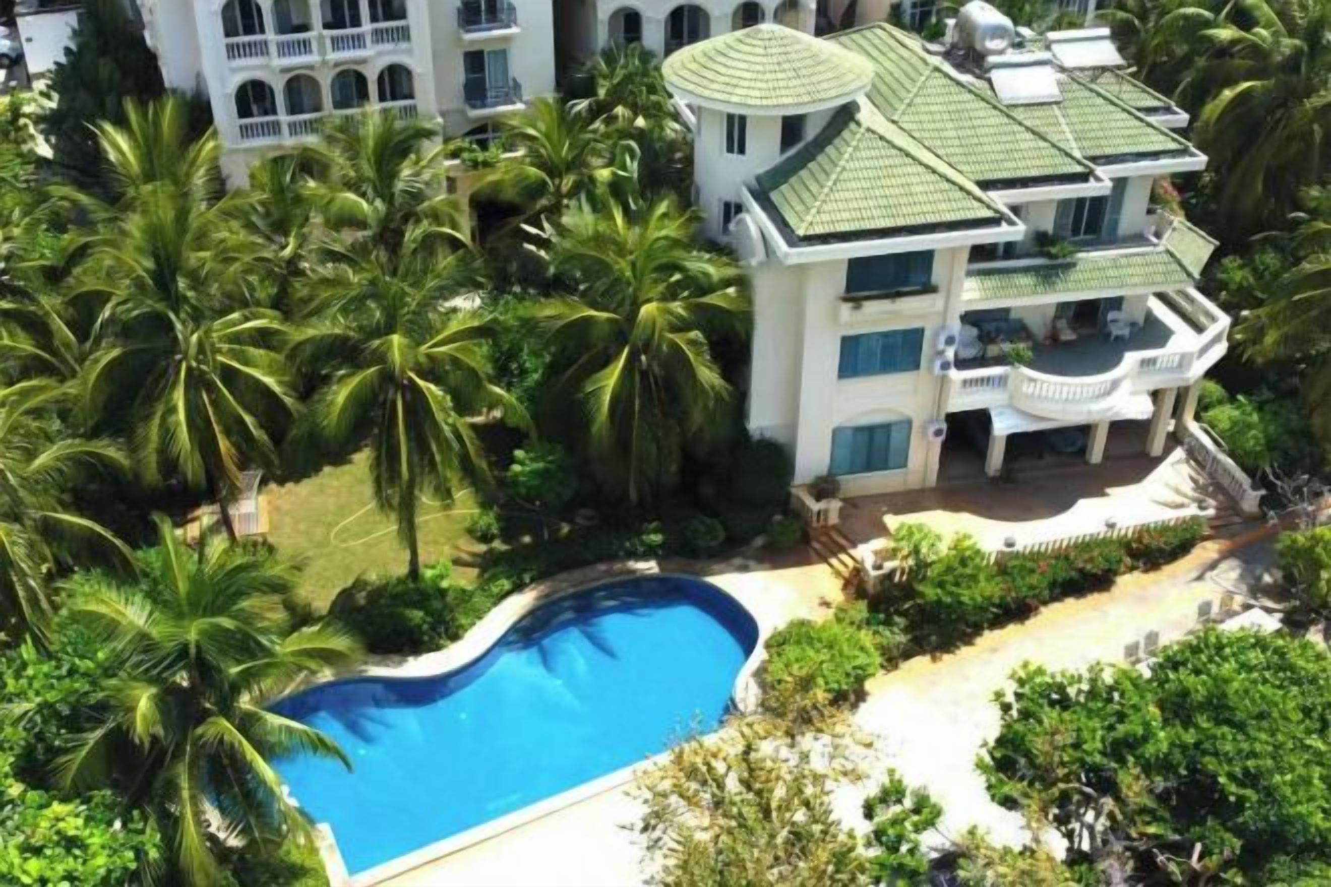 A multi-story building with a swimming pool surrounded by palm trees.