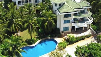 A multi-story building with a swimming pool surrounded by palm trees.