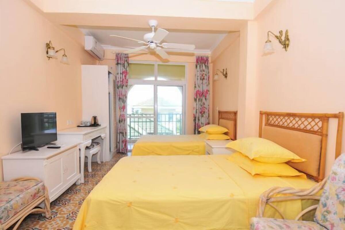 Une chambre d’hôtel avec deux lits, une télévision, un bureau et un balcon avec vue.