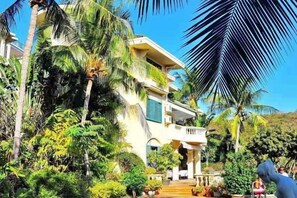 A multi-story building with a balcony, surrounded by lush greenery and palm trees. - Venus Garden Villa(Sanya Dadonghai Summer Department) (Sanya)