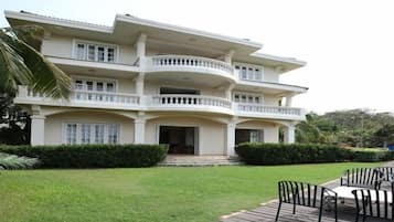 A multi-story building with a large front porch, a covered outdoor seating area, and a well-maintained lawn.